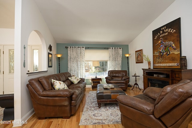 living area featuring light wood finished floors, baseboards, and vaulted ceiling