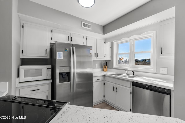 kitchen featuring visible vents, white cabinets, appliances with stainless steel finishes, and a sink