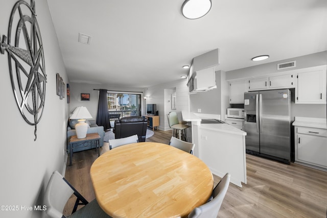 dining space with light wood-style flooring and visible vents