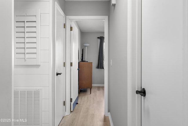 hall featuring visible vents, baseboards, and light wood-style floors