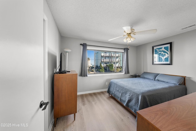 bedroom featuring visible vents, baseboards, a textured ceiling, and light wood finished floors