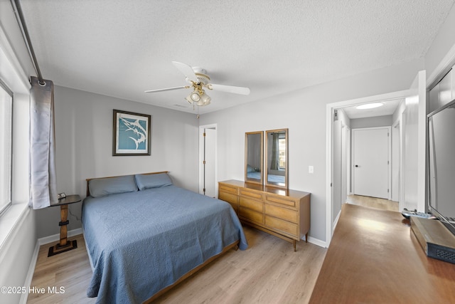 bedroom featuring a ceiling fan, baseboards, light wood-type flooring, and a textured ceiling