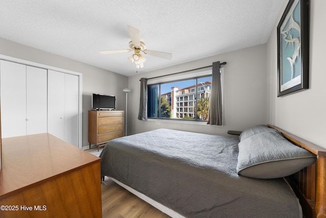 bedroom with a closet, a textured ceiling, a ceiling fan, and wood finished floors