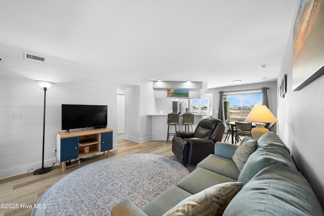 living area with light wood-type flooring, baseboards, and visible vents