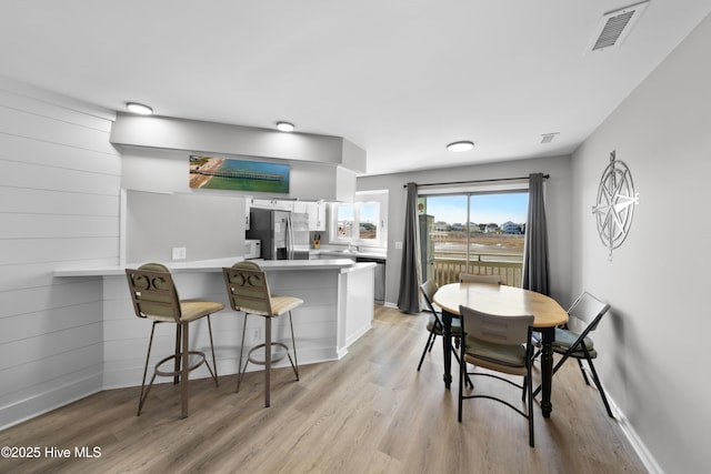 dining room with baseboards, visible vents, and light wood-type flooring