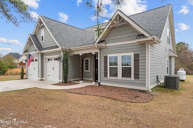 view of front facade featuring an attached garage, central AC, driveway, roof with shingles, and a front yard