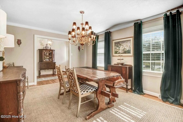 dining room with baseboards, crown molding, light wood finished floors, and an inviting chandelier