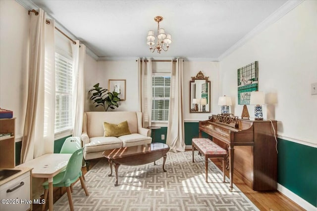 living area featuring baseboards, ornamental molding, wood finished floors, and an inviting chandelier