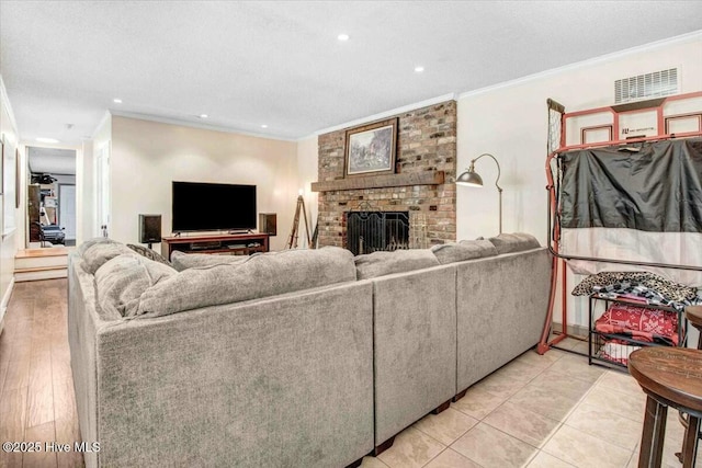 living room featuring ornamental molding, a brick fireplace, visible vents, and a textured ceiling