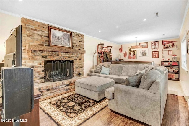 living area with recessed lighting, wood finished floors, visible vents, ornamental molding, and a brick fireplace