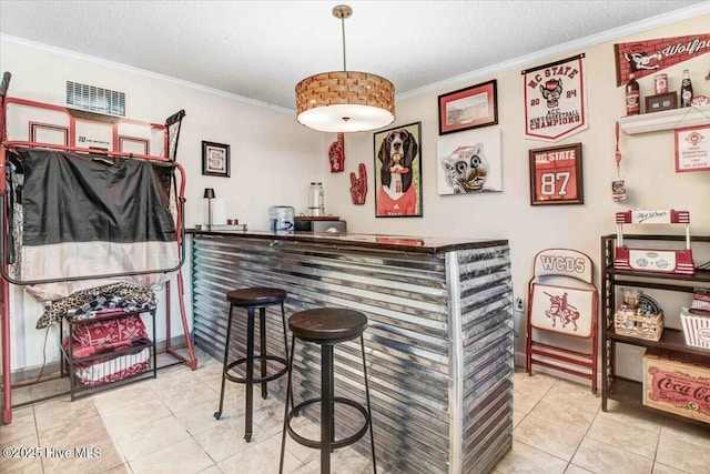 bar featuring ornamental molding, a bar, a textured ceiling, and light tile patterned flooring