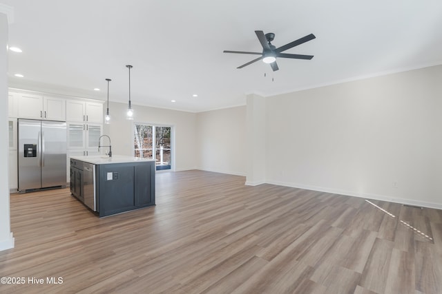 kitchen featuring built in refrigerator, white cabinets, open floor plan, light countertops, and light wood finished floors