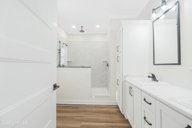 full bathroom with a walk in shower, recessed lighting, wood finished floors, a sink, and double vanity