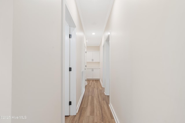 hall featuring light wood-type flooring, baseboards, crown molding, and recessed lighting