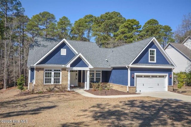 craftsman house with roof with shingles, concrete driveway, and brick siding