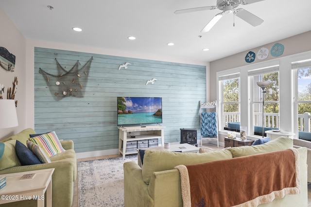 living room with a ceiling fan, recessed lighting, wooden walls, and baseboards