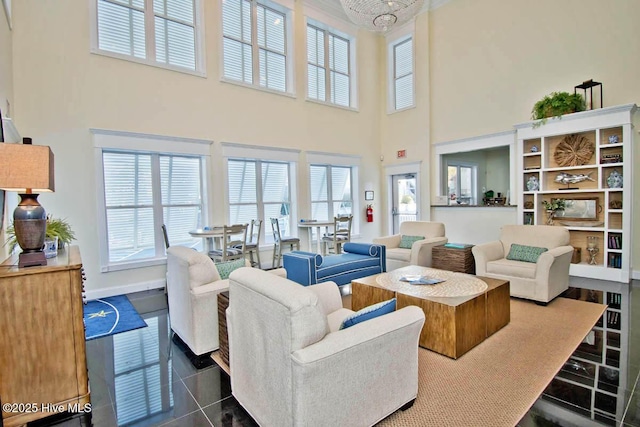 living area featuring dark tile patterned floors, plenty of natural light, a high ceiling, and baseboards