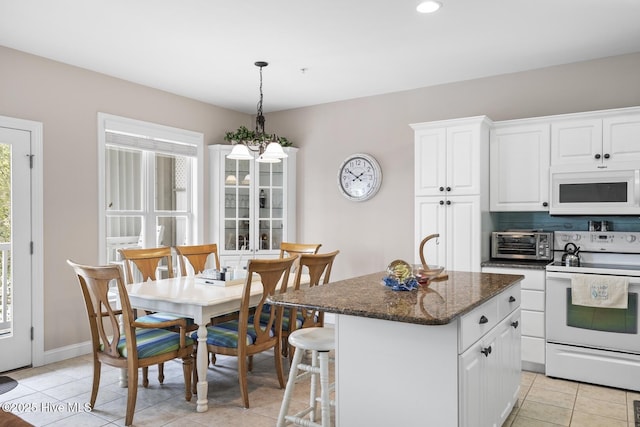 kitchen featuring white appliances, light tile patterned floors, a toaster, white cabinets, and a kitchen island