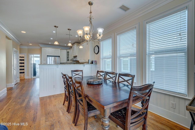 dining area with recessed lighting, crown molding, visible vents, light wood-style floors, and an inviting chandelier