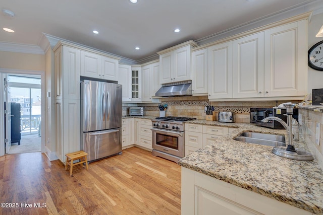 kitchen featuring decorative backsplash, ornamental molding, extractor fan, stainless steel appliances, and a sink