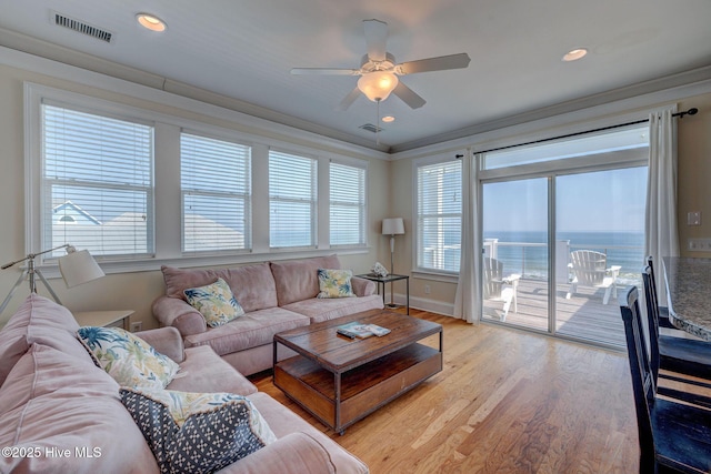 living room featuring ornamental molding, a water view, visible vents, and light wood-style floors