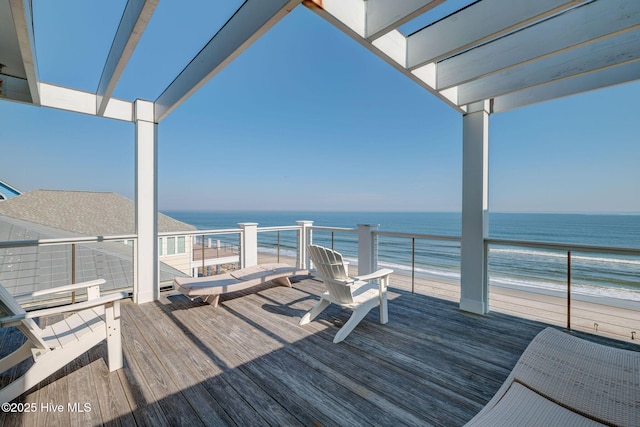 wooden terrace with a water view and a view of the beach