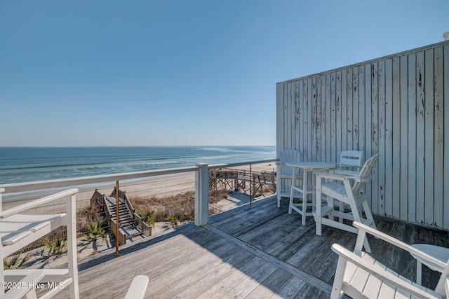 wooden deck with a water view and a beach view