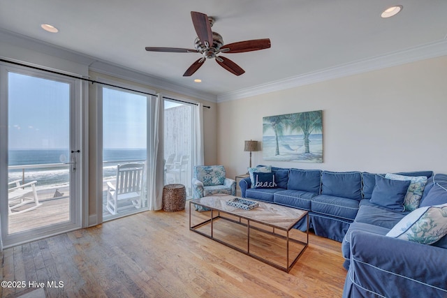 living room with recessed lighting, a water view, wood finished floors, and crown molding