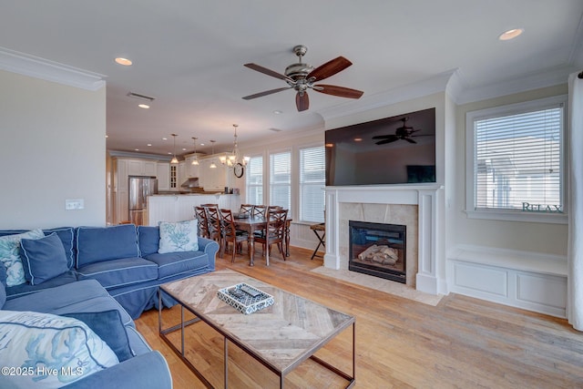 living area with visible vents, light wood-style flooring, ornamental molding, a fireplace, and recessed lighting