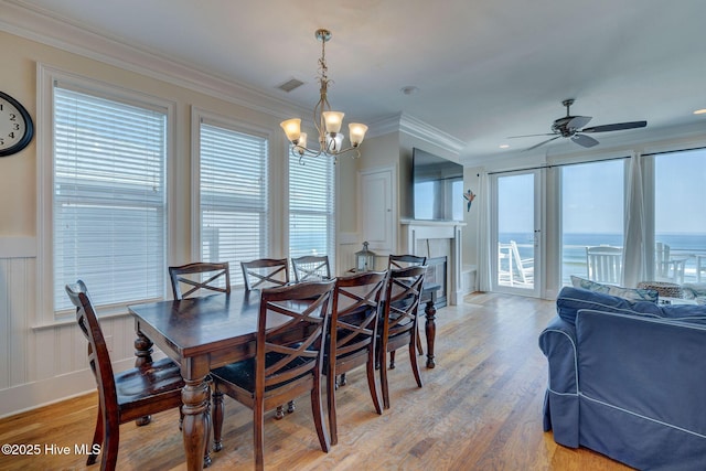 dining room with a healthy amount of sunlight, crown molding, visible vents, and light wood finished floors