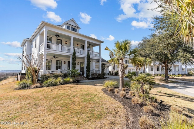 view of front of home with ceiling fan, fence, a porch, and a front lawn