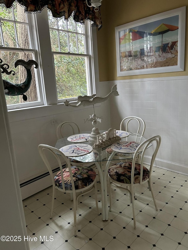 dining room featuring wainscoting, baseboard heating, tile walls, and tile patterned floors