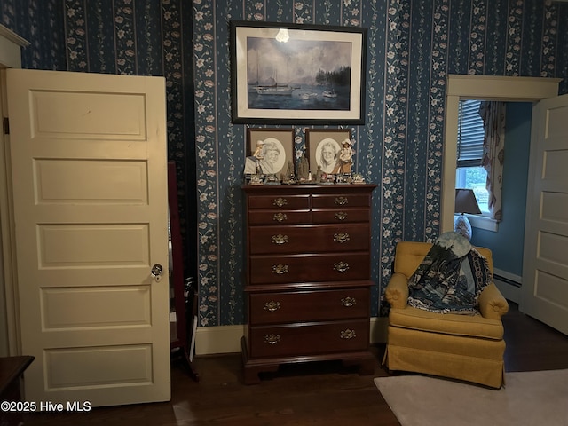 living area with wallpapered walls, a baseboard radiator, baseboards, and dark wood-style flooring