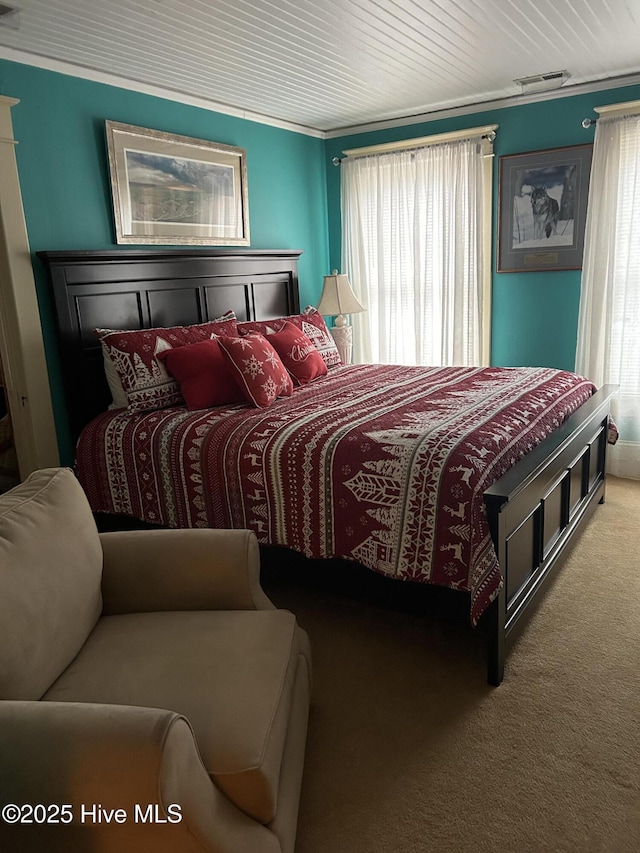 bedroom with carpet floors, visible vents, and crown molding