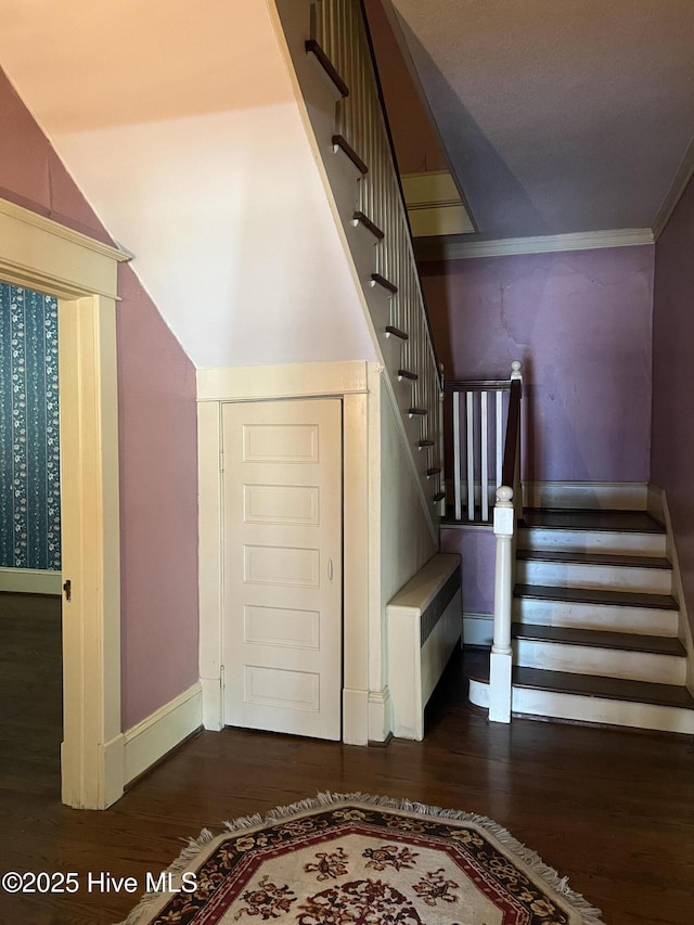 staircase featuring ornamental molding, wood finished floors, and baseboards