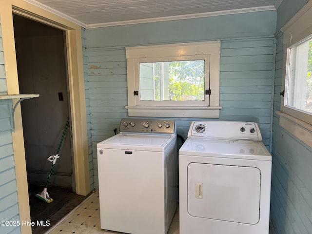 laundry area featuring laundry area, wood walls, washer and dryer, ornamental molding, and light floors