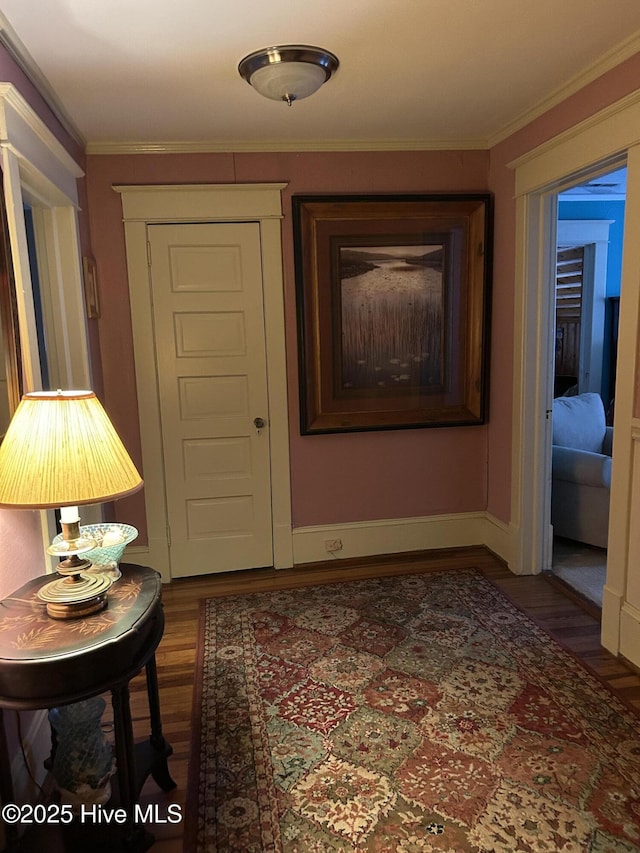 hallway featuring crown molding, baseboards, and wood finished floors