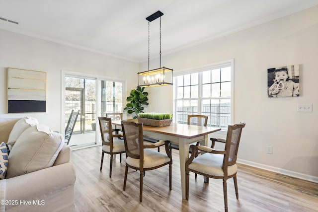 dining room featuring crown molding, light wood finished floors, visible vents, an inviting chandelier, and baseboards