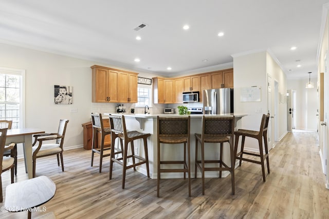 kitchen with visible vents, decorative backsplash, appliances with stainless steel finishes, a breakfast bar area, and light countertops