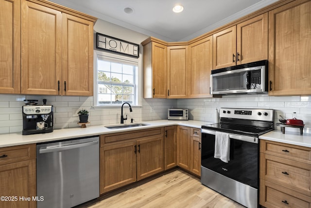 kitchen with appliances with stainless steel finishes, light countertops, a sink, and backsplash