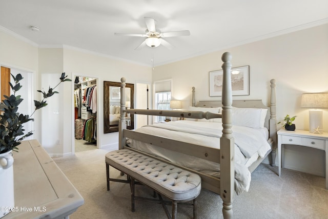 bedroom with a closet, light colored carpet, a spacious closet, ornamental molding, and a ceiling fan