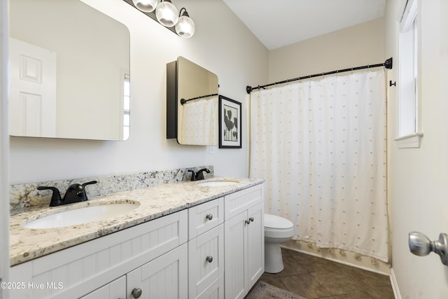 full bath featuring toilet, double vanity, a sink, and tile patterned floors