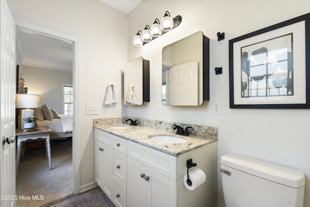 ensuite bathroom with double vanity, a sink, toilet, and connected bathroom