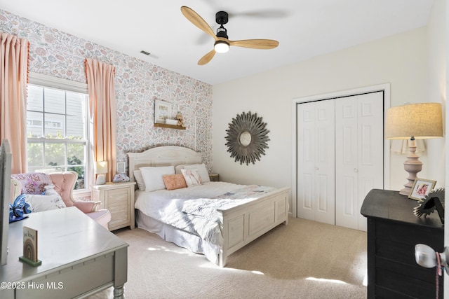 bedroom featuring light carpet, wallpapered walls, visible vents, and a closet