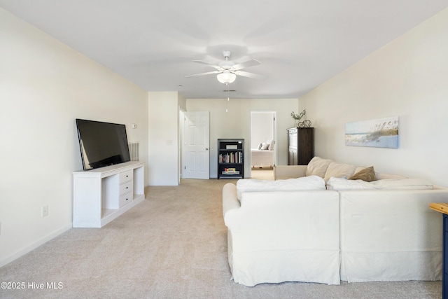 living area with a ceiling fan, light carpet, and baseboards