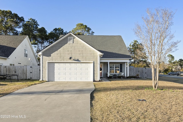 view of front of house with an attached garage, fence, concrete driveway, roof with shingles, and a front yard