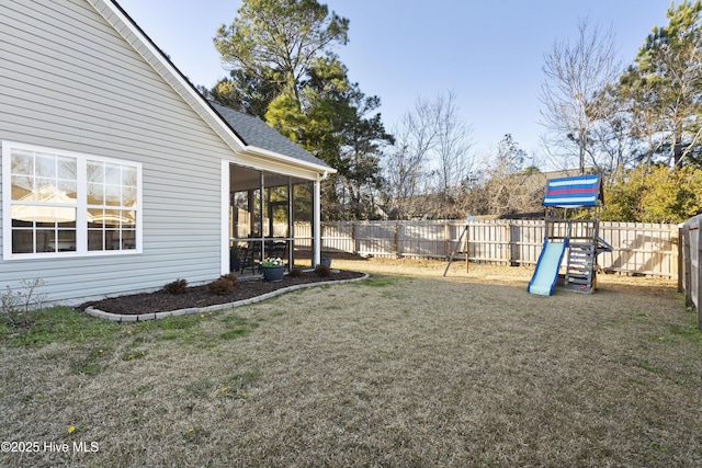 view of yard featuring a playground, a fenced backyard, and a sunroom