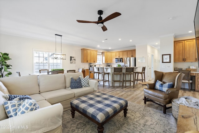 living area featuring plenty of natural light, ceiling fan with notable chandelier, light wood-style flooring, and recessed lighting