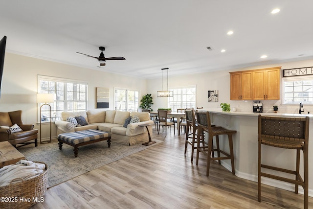 living room with crown molding, recessed lighting, visible vents, ceiling fan, and light wood-type flooring