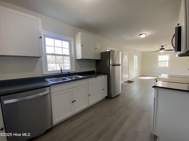 kitchen featuring appliances with stainless steel finishes, dark countertops, white cabinetry, and a sink